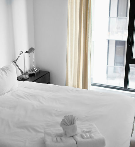 Freshly made bed with folded towels in a bright city apartment
