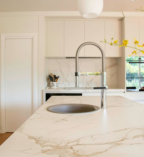 Bright kitchen with a marble island and a brushed steel faucet