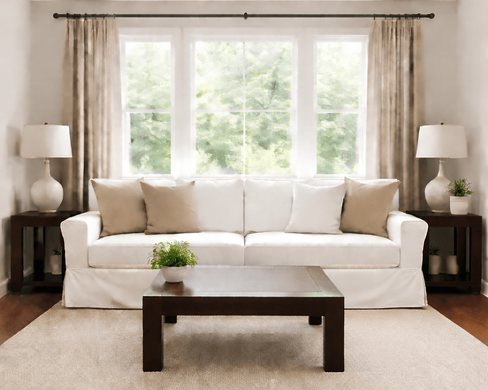 Neutral living room with white sofa, beige pillows, table lamps, and large window showing balanced interior design elements of light, color, and symmetry.