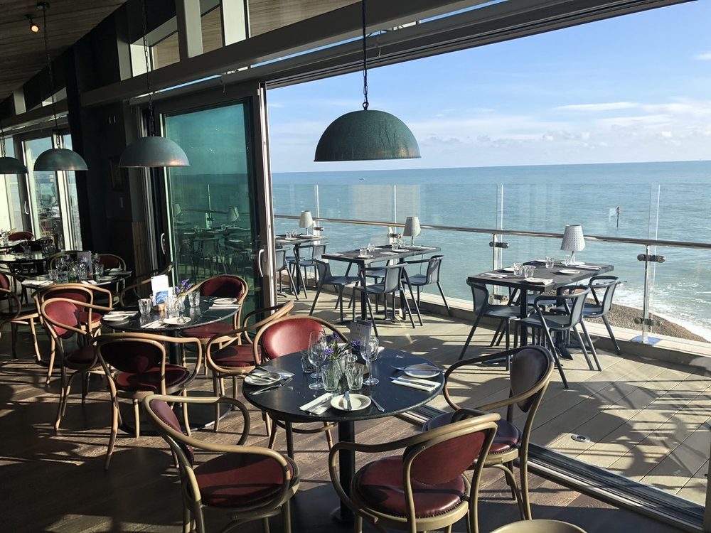 Seafront restaurant with tables laid on a sunny terrace overlooking the sea