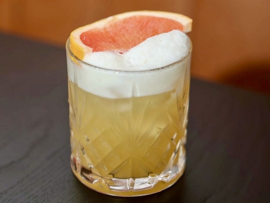 A grapefruit sour cocktail topped with foam and a slice of grapefruit