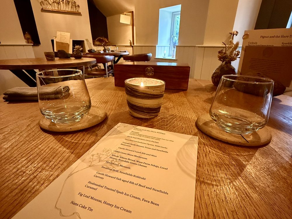 Candlelit table in a country restaurant with a printed tasting menu and two glasses