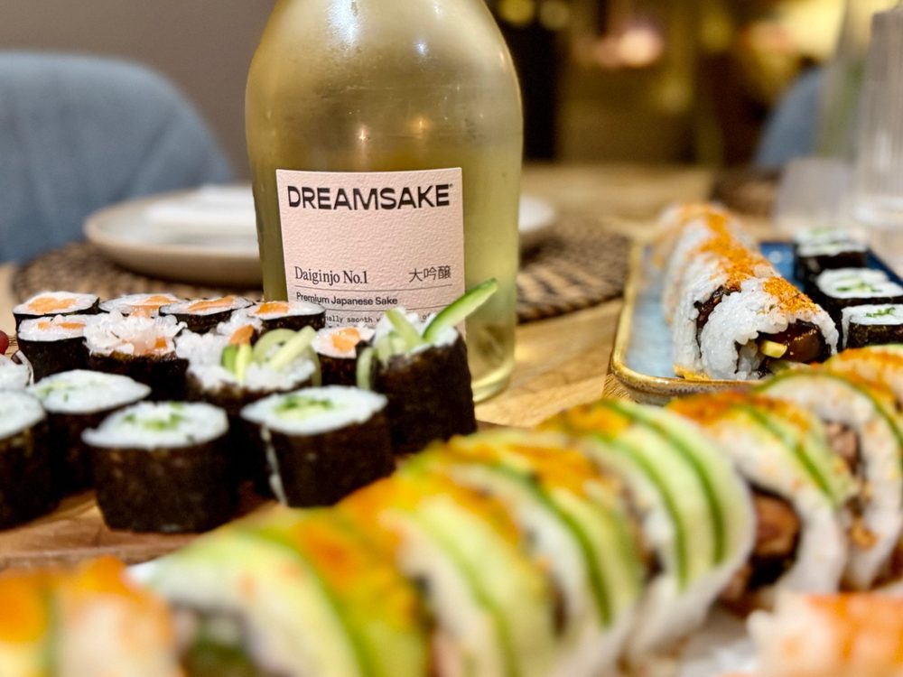 A selection of sushi rolls on a table with a chilled bottle of sake
