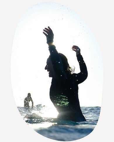 Deb McMenamin on a surfboard in the ocean, gathering inspiration for her coastal paintings