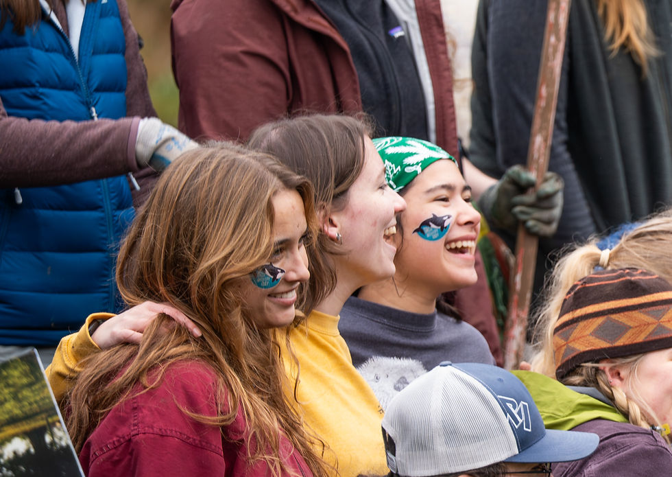 A group of three women smile with Orca Recovery Day temporary tattoos on.