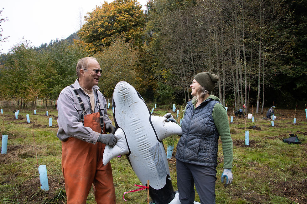 A man and woman hold an inflatable orca and look at each other.
