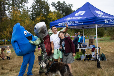 People take a selfie with a mascot salmon and raindrop.