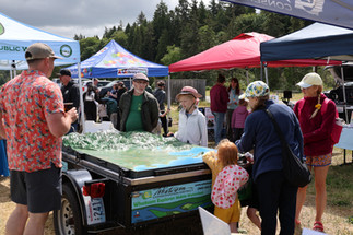 People gather around a topographic map surrounded by booths.