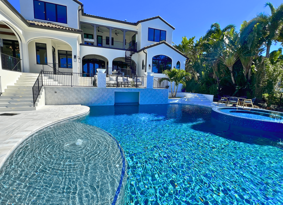 10' deep pool with a rain curtain grotto, sunshelf, 360 spillover spa, and marble decking. 