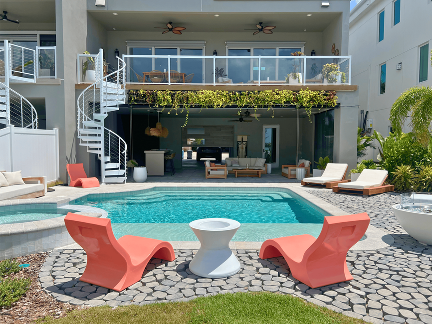 Leslie Davis and Lyndsay Lamb's Patio & Pool Space Featuring A Freeform Pool With A Spillover Spa, CobbleStone Decking, & Tropical Landscaping From Season 5 of Rock The Block