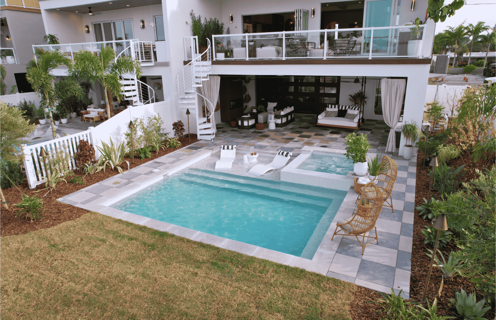 Custom Outdoor Living Space Featuring A Linear Pool, Sunshelf With Loungers, Spillover Spa, Checker Board Paver Patio, & Florida Friendly Landscaping In Pinellas County