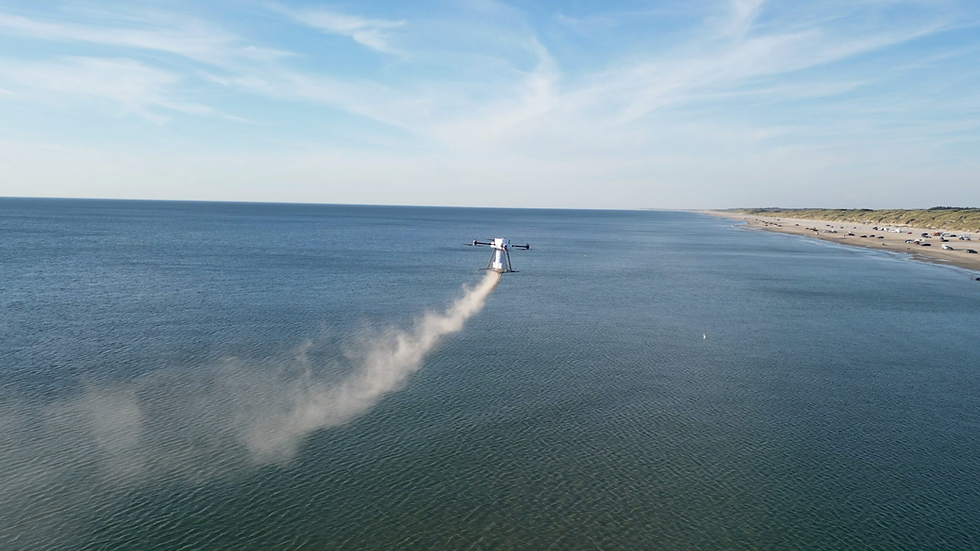 Air Funerals specialbygget drone der spreder aske over 3. revle ved Blokhus og stranden med biler til höjre i billedet.