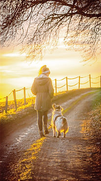 woman in brown coat holding white dog on brown dirt road during sunset_edited.jpg