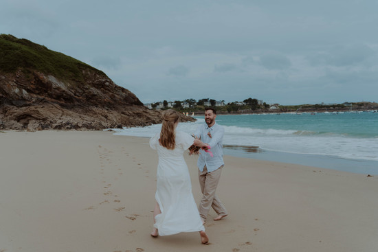 Audrey et Nicolas courant sur le sable lors de leur séance photo à Saint Lunaire, Bretagne