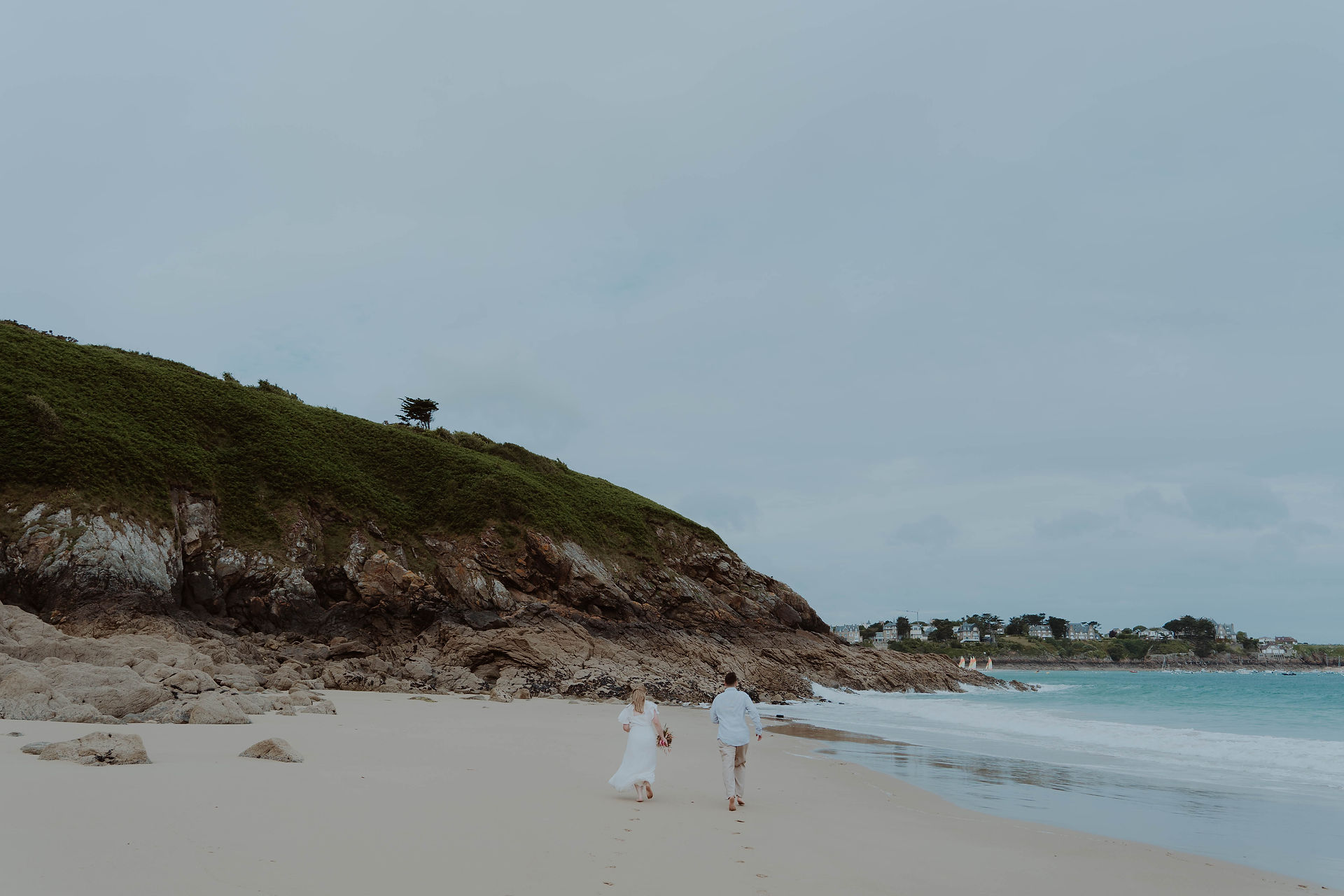 Audrey et Nicolas courant sur le sable lors de leur séance photo à Saint Lunaire, Bretagne