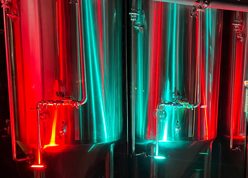 Brewery tanks lighted up with red and green lights.