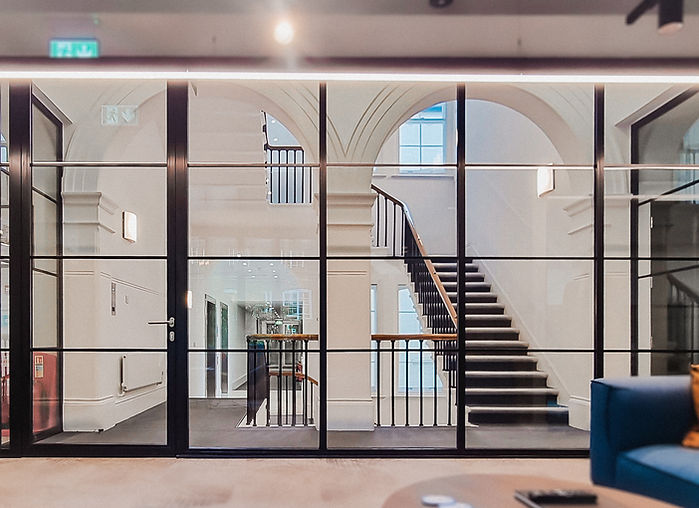 Internal black framed fire-rated glass doors leading into grand classical hallway