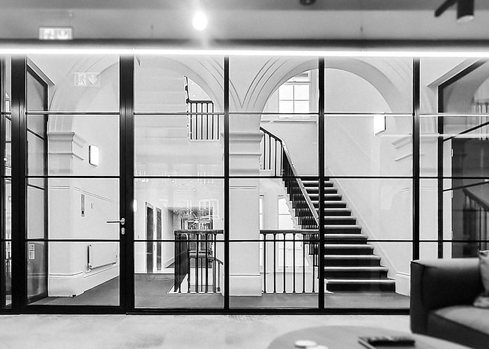 Internal black framed fire-rated glass doors leading into grand classical hallway