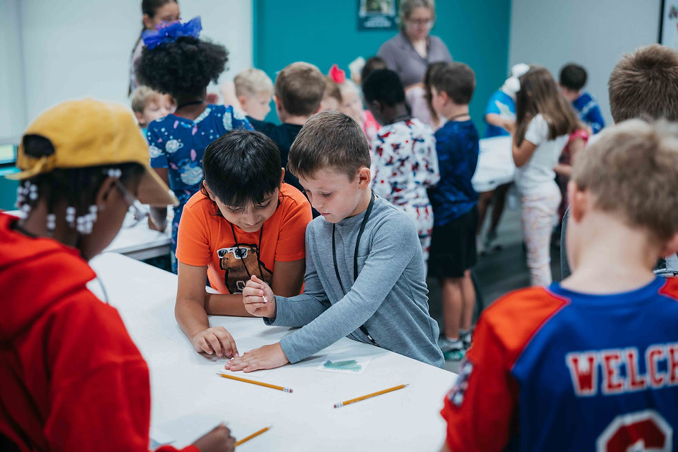 Two young children color a page together in a classroom.