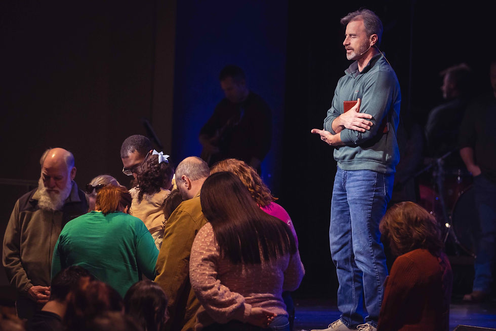 A pastor prays over families and their children.