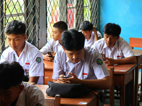 Students sitting in a classroom staring intently on their mobile phones
