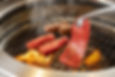 A grill filled with bite-sized pieces of meat being cooked at a Yakiniku restaurant.