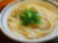 A bowl of Sanuki udon with thick, firm noodles served in a light broth.
