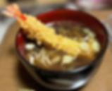 A bowl of toshikoshi soba, Japanese New Year’s Eve noodles, topped with a crispy tempura prawn and garnished with sliced green onions.