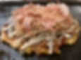 A savory Osaka-style okonomiyaki pancake topped with sauce, mayonnaise, and bonito flakes.