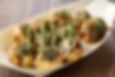 A plate of takoyaki, ball-shaped snacks filled with octopus, served with sauces and bonito flakes.
