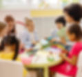 Groupe d'enfants assis autour d'une table ronde colorée, faisant des activités artistiques