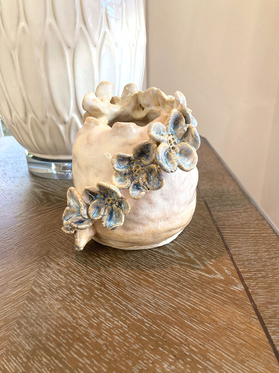 Thumbnail: White and Blue Round Ceramic Vase with organic shaped handmade flowers on an end table next to a white lamp