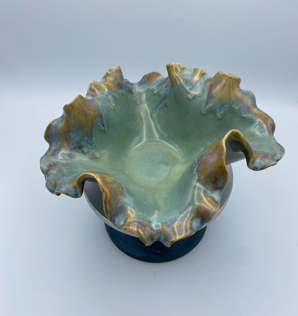 Handbuilt turquoise and brown wavy ceramic bowl with ruffled edges and glossy glaze, stoneware art piece.