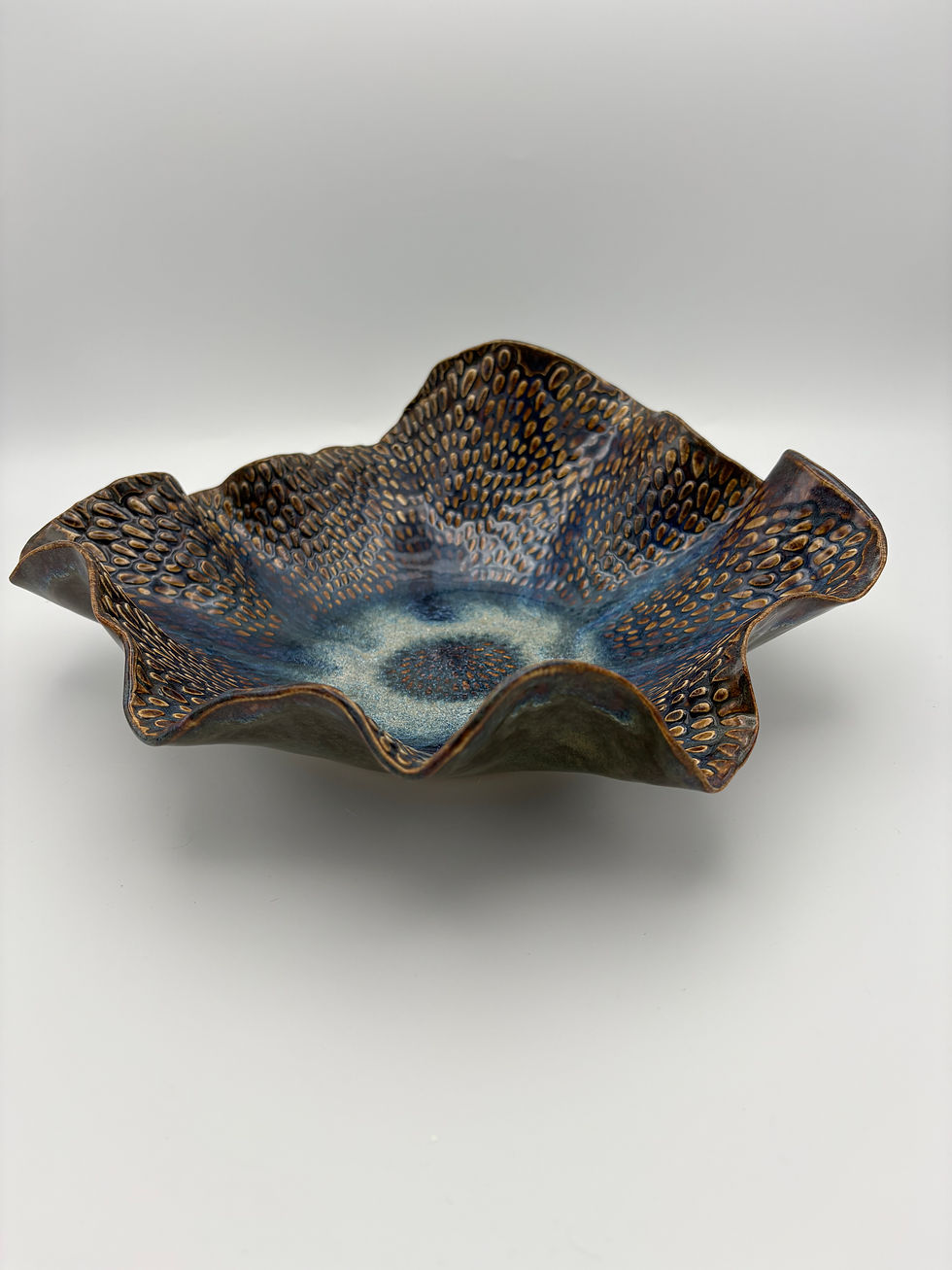 Textured ceramic bowl with ruffled wavy edge, glazed in caramel, blue, rust, and cream tones