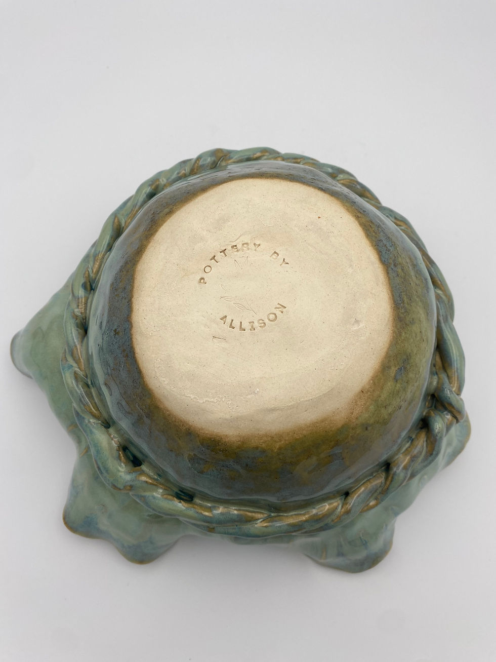 Thumbnail: Green and blue ceramic bowl with wavy edges, resembling a flower, with a rope detail going around base.