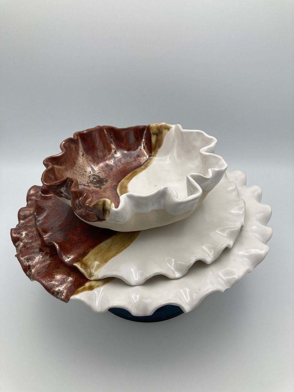 Thumbnail: A set of two handmade ceramic plates and one bowl that is glazed with white and copper colors