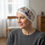 Thumbnail: a woman wearing cream chemo headwear with a pink floral headband