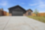 Dark board-and-batten home with red brick and black garage door