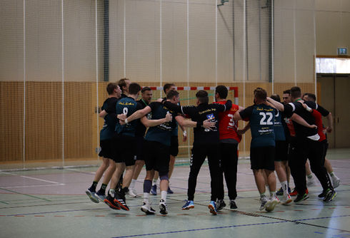 Team von Handball-Spielern stehen im Kreis und freuen sich