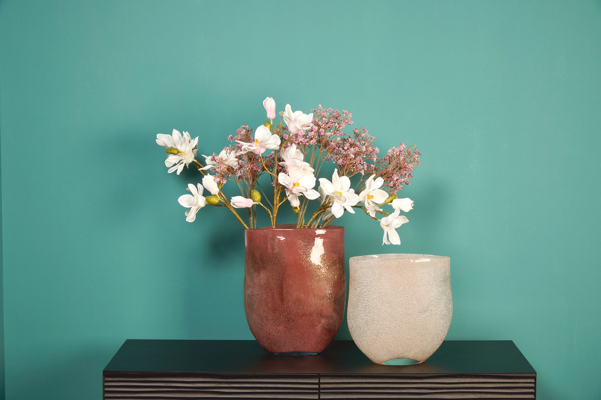 Vase creme und rot/orange mit Blumen auf schwarzem Tisch