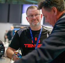 Person smiling at a convention, showing a smartphone