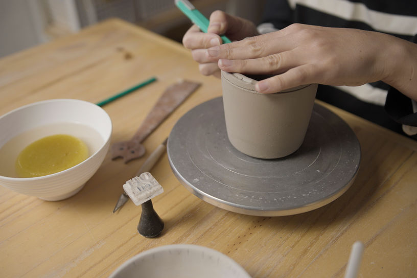 Artesano corta el borde del vaso. Herramientas en mesa, Taller de cerámica.