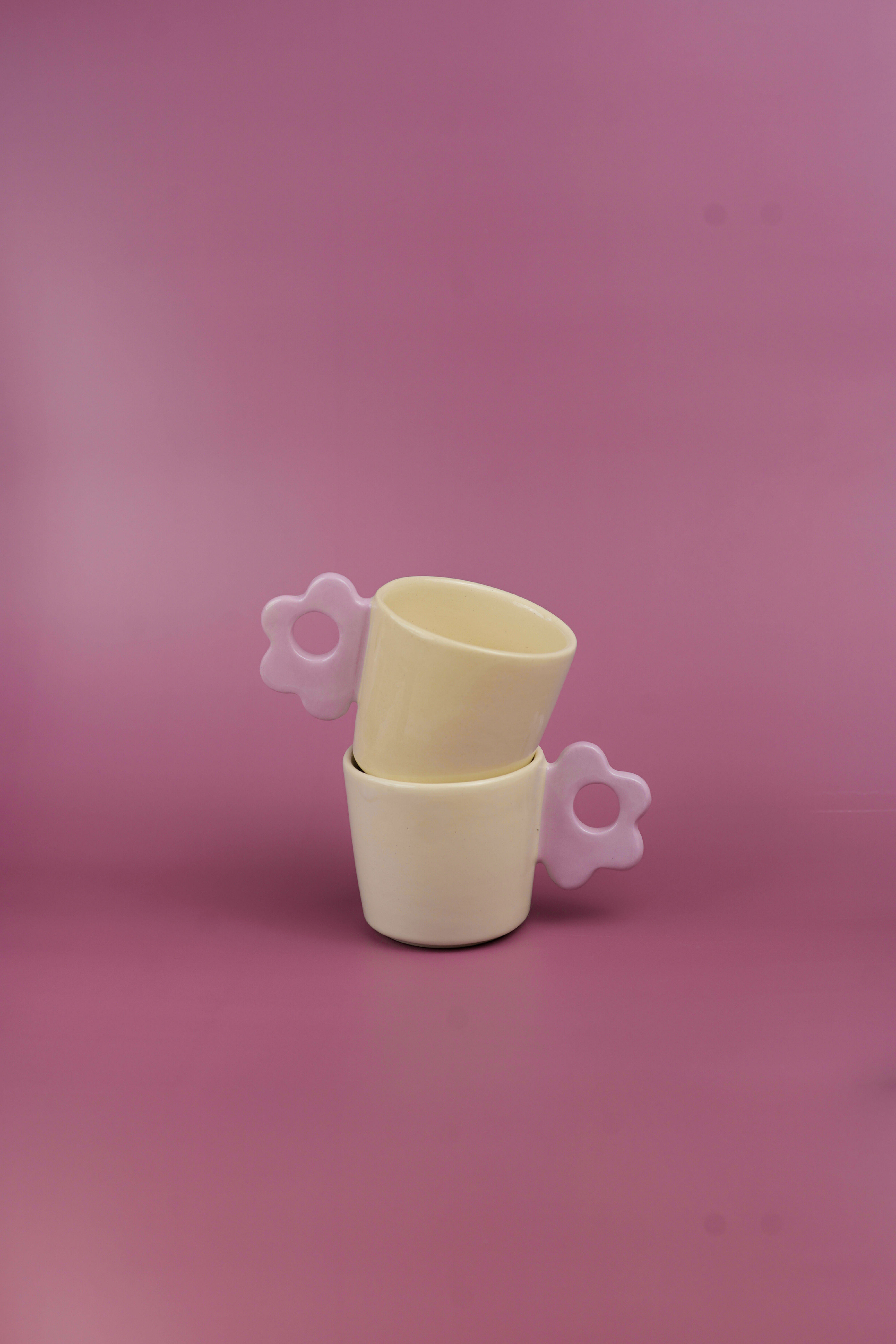 Dos tazas apiladas, amarillas y rosas, sobre fondo fucsia. Ohdella!
