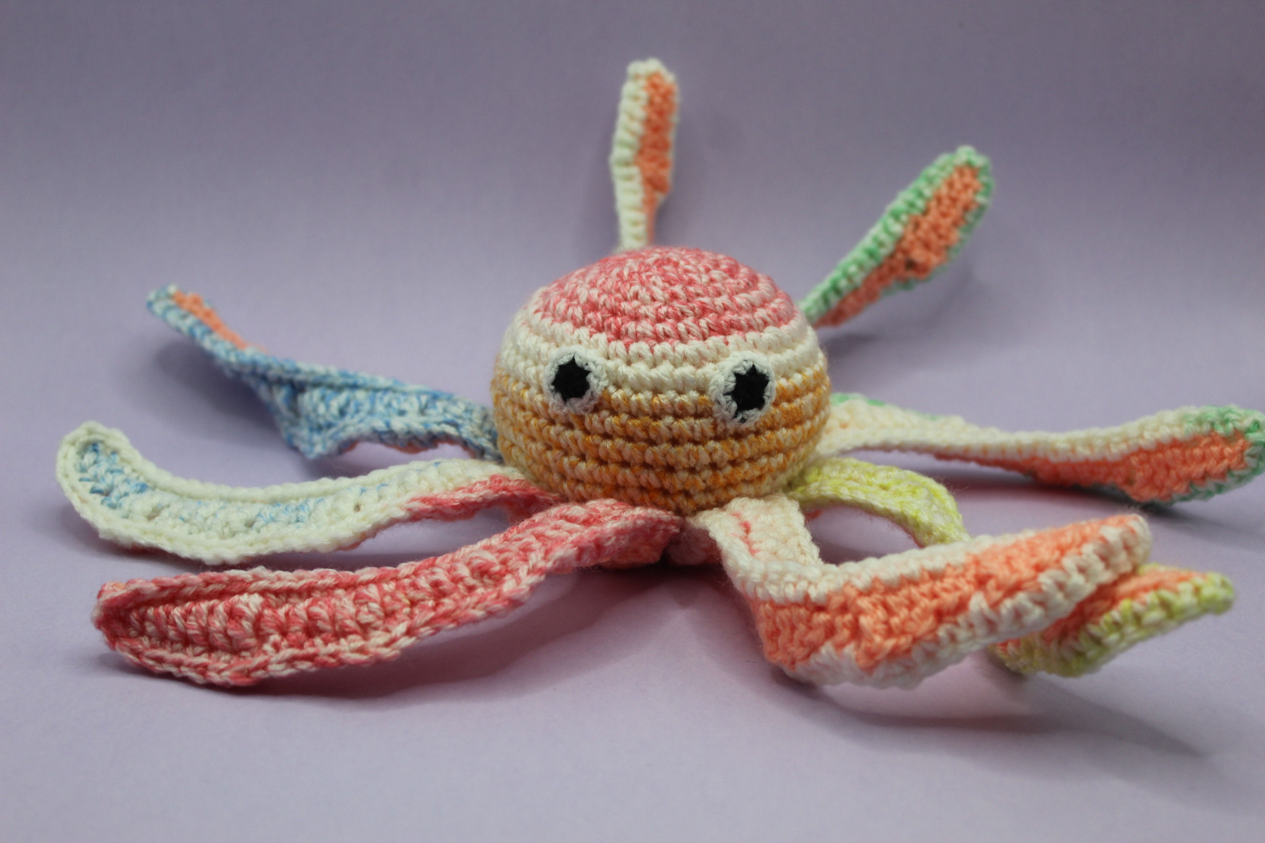 Crochet  soft toy octopus. In a pink mixed and white yarn.