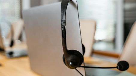 Ein Headset an einem Laptopbildschirm als Symbolbild für die Anrufererkennung beim IT-Support.