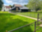 estate fencing enclosing lush green grass with a back drop of a large farmhouse