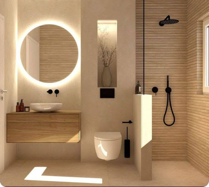 Modern beige bathroom with glowing round mirror, floating wood vanity, wall toilet, and black shower fixtures.