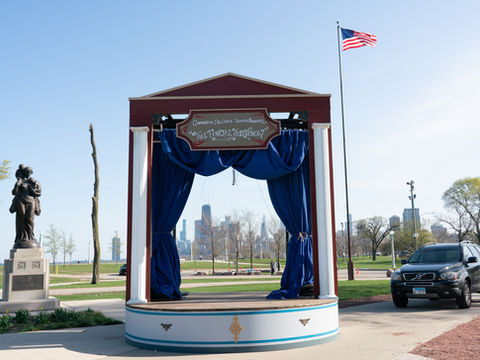Life sized Puppet stage set up in park with Chicago skyline behind.