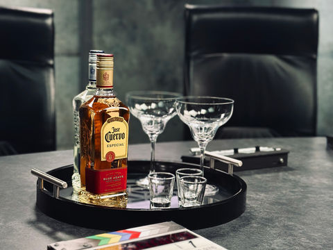 Jose Cuervo tequila bottle with glasses on table and film slate in foreground on set