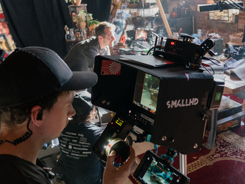 Camera operator holding focus wheel while viewing footage on SmallHD monitor.